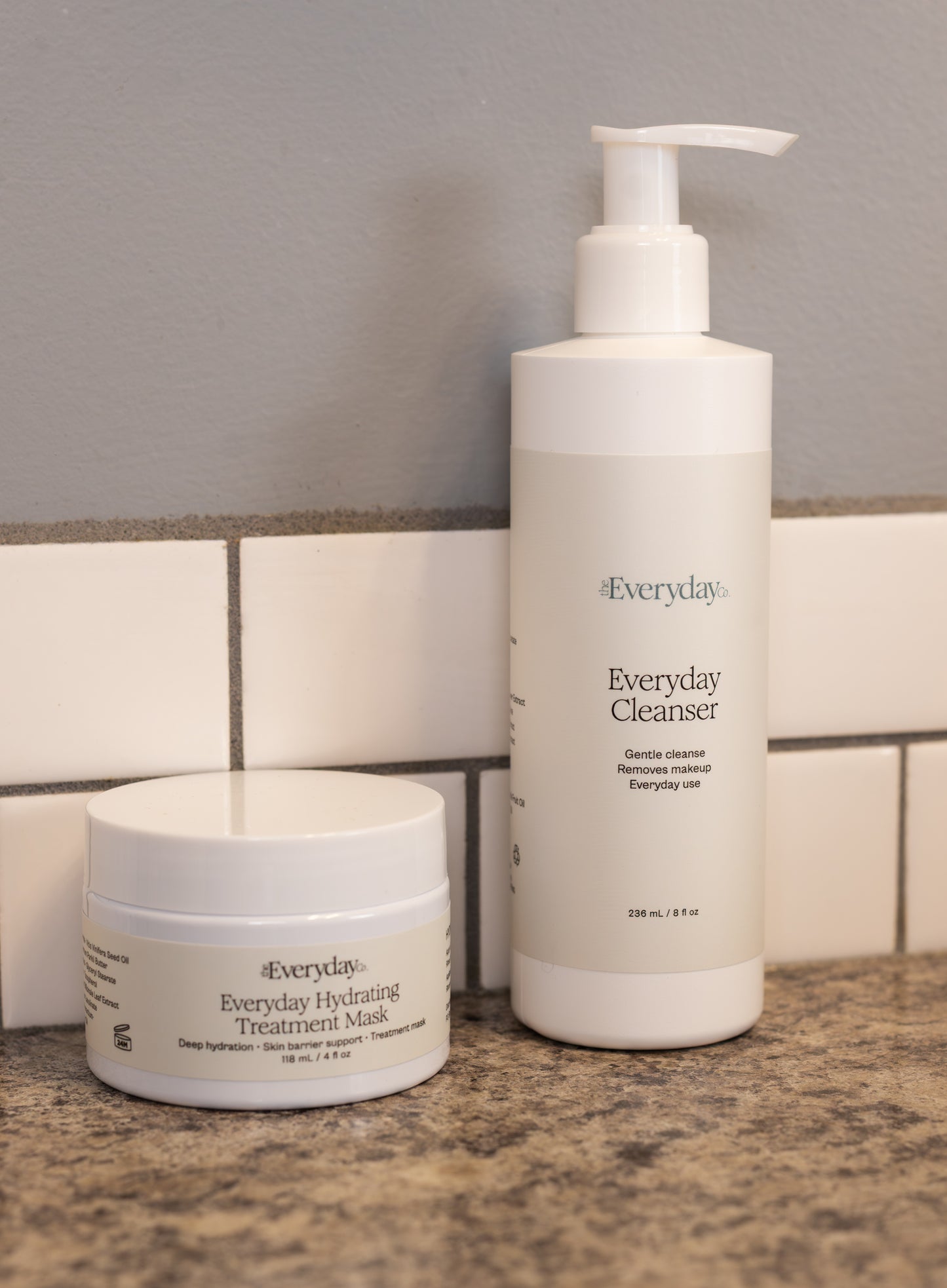 Two skincare products, 'Everyday Cleanser' and 'Everyday Hydrating Treatment Mask', on a bathroom counter.