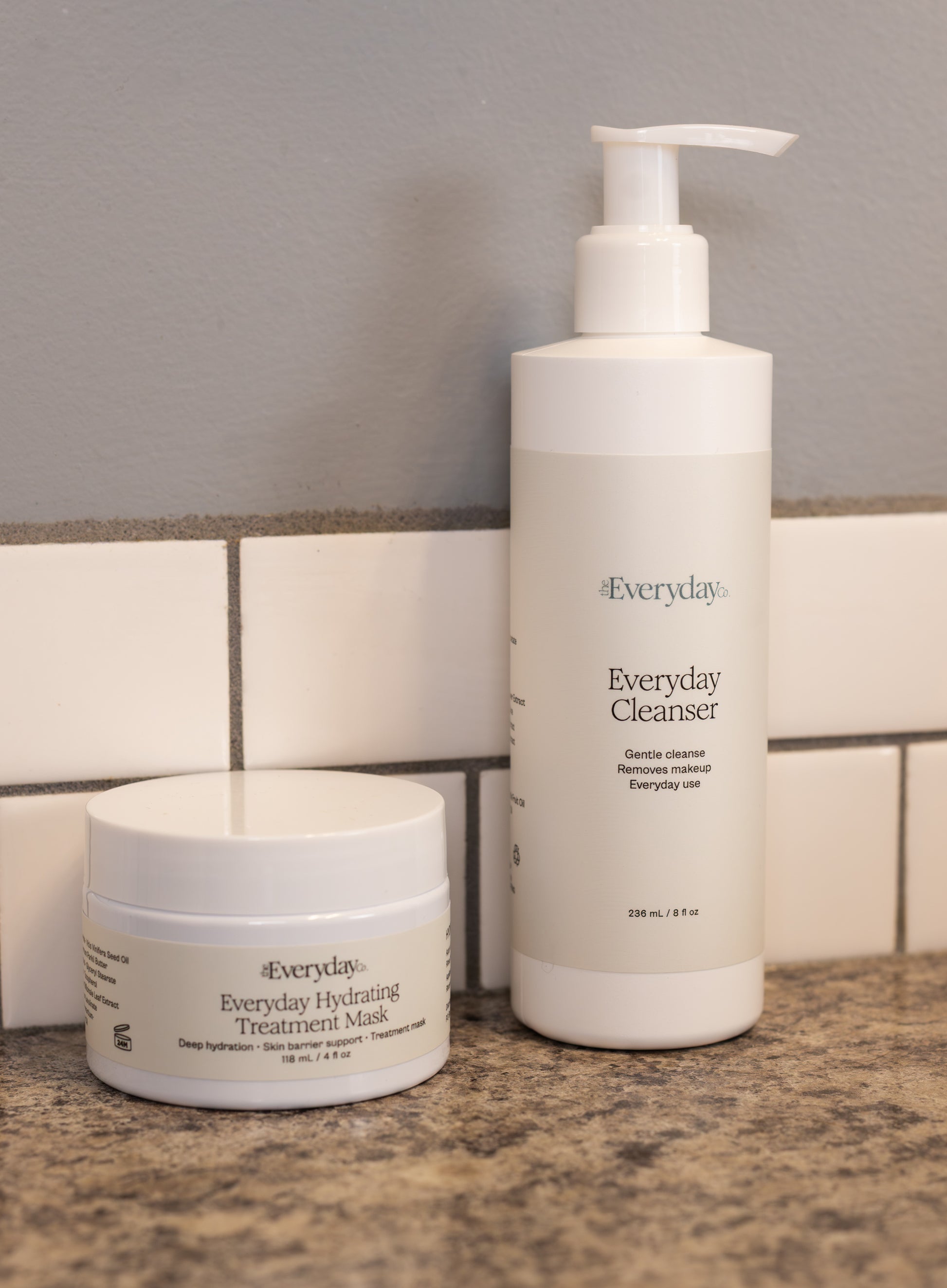 Two skincare products, 'Everyday Cleanser' and 'Everyday Hydrating Treatment Mask', on a bathroom counter.